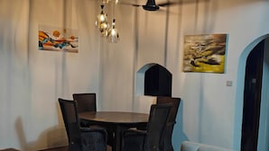 Een eetgedeelte met een ronde tafel en stoelen, een bank en kunstwerken aan de muur.