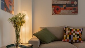 A living room with a sofa, a table with a vase of flowers, and a lamp. - Tripoli White Home by Wonderful Italy (Turin)