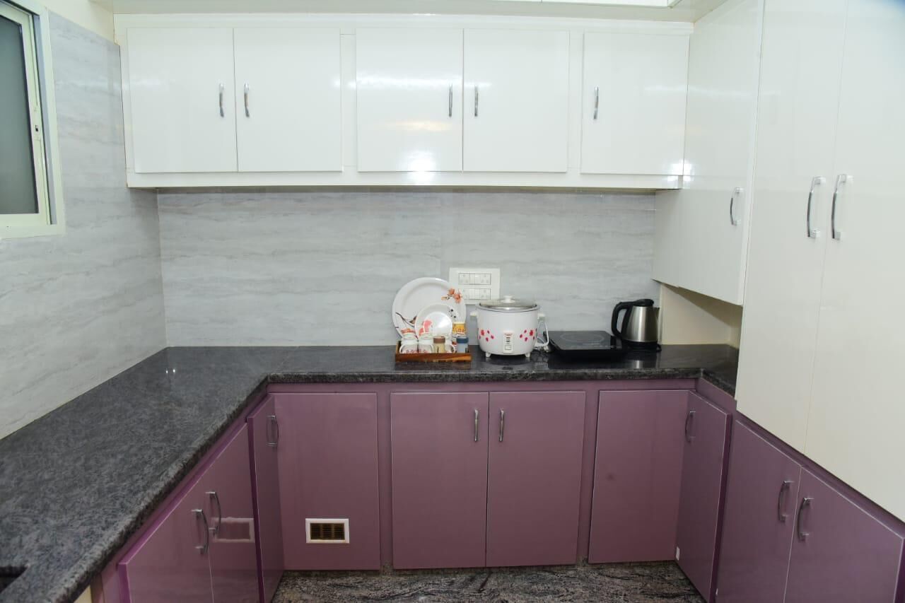 A kitchen with white upper cabinets, a granite countertop, and purple lower cabinets.