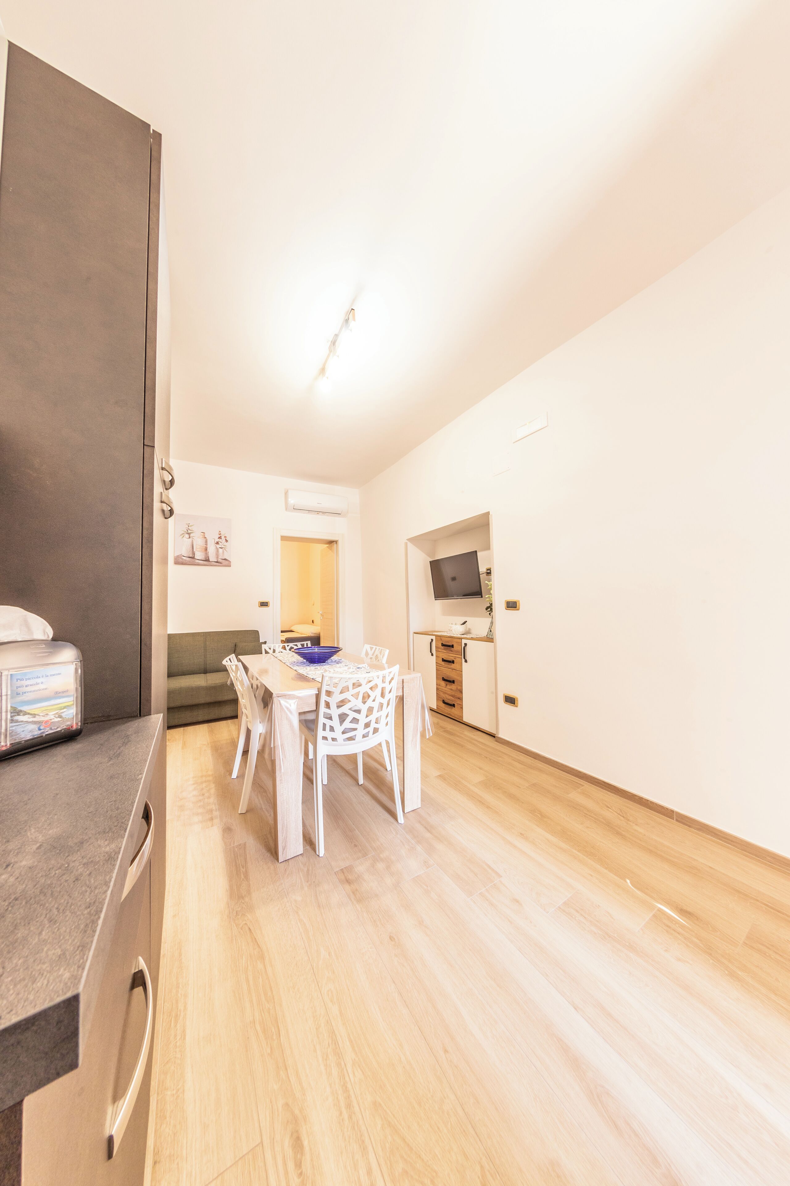 A compact kitchen with a dining area, a built-in oven, and a TV on the wall.