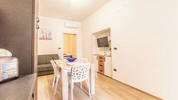 A compact kitchen with a dining area, a built-in oven, and a TV on the wall.