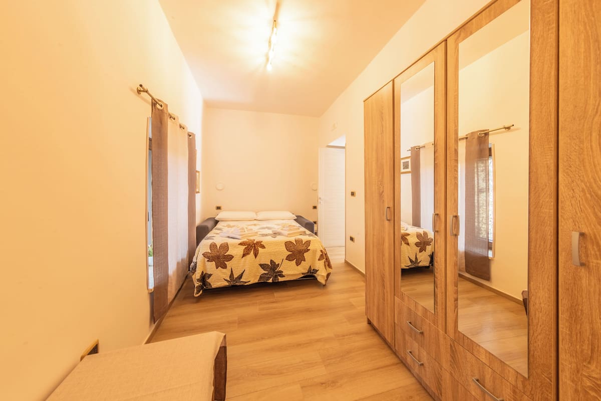 A bedroom with a bed, wooden wardrobe, and a mirror.