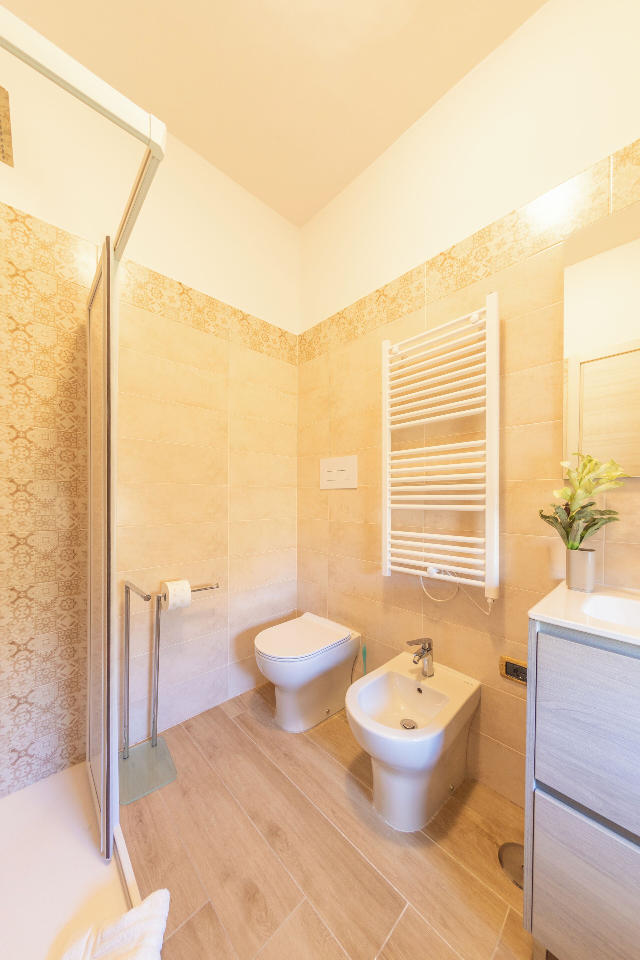 Un baño moderno con cabina de ducha de vidrio, un bidé, un lavabo y un espejo.