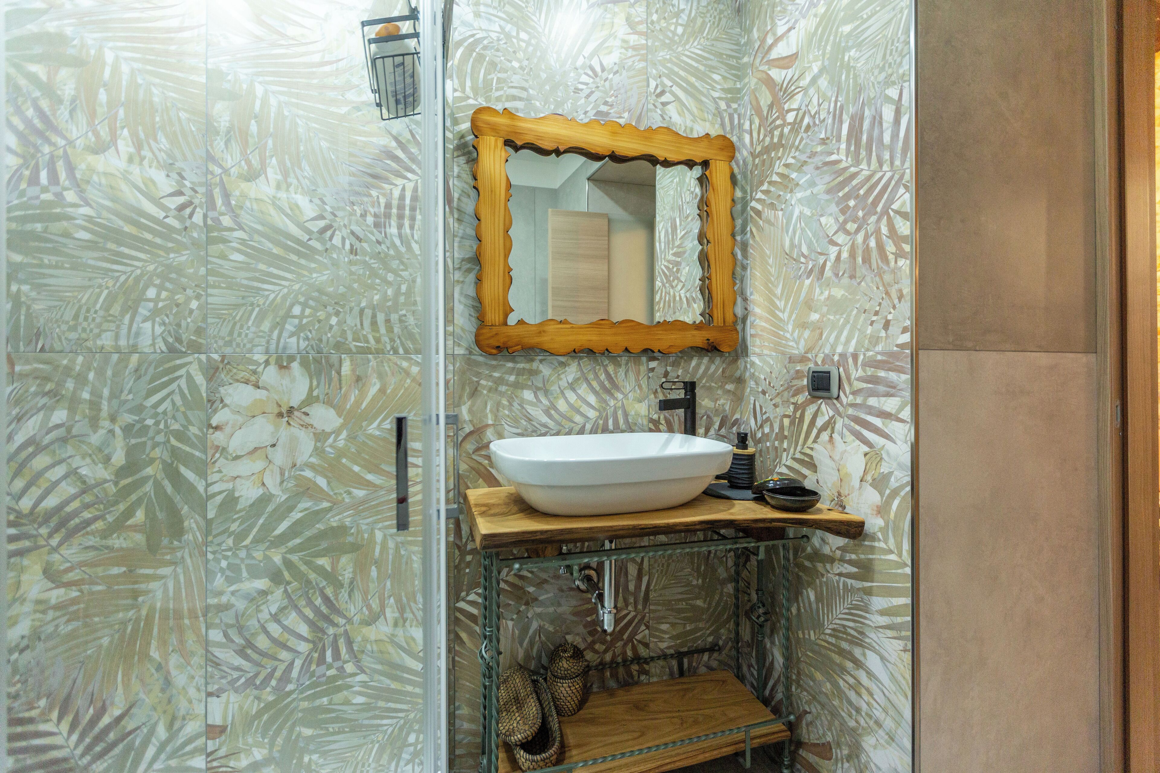 A bathroom with a large mirror, a white sink, and a wooden vanity.