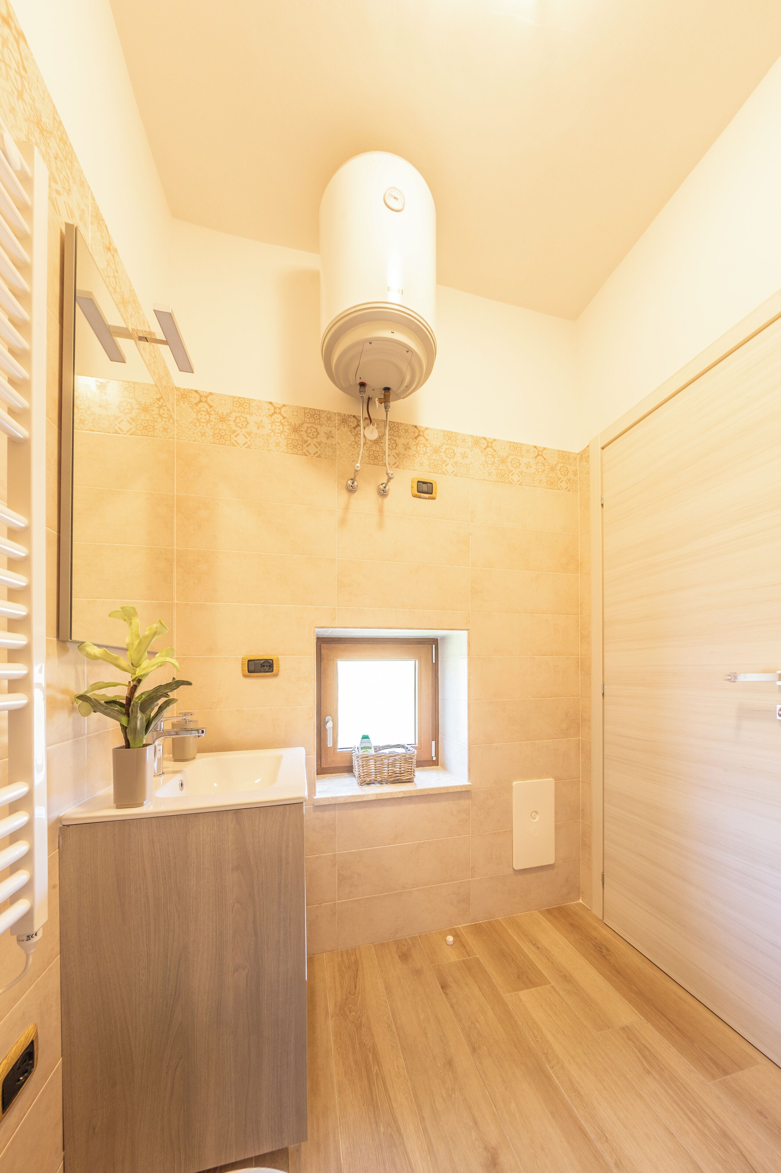 A modern bathroom with a wooden vanity, a small window, and a towel rack.