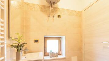 A modern bathroom with a wooden vanity, a small window, and a towel rack.