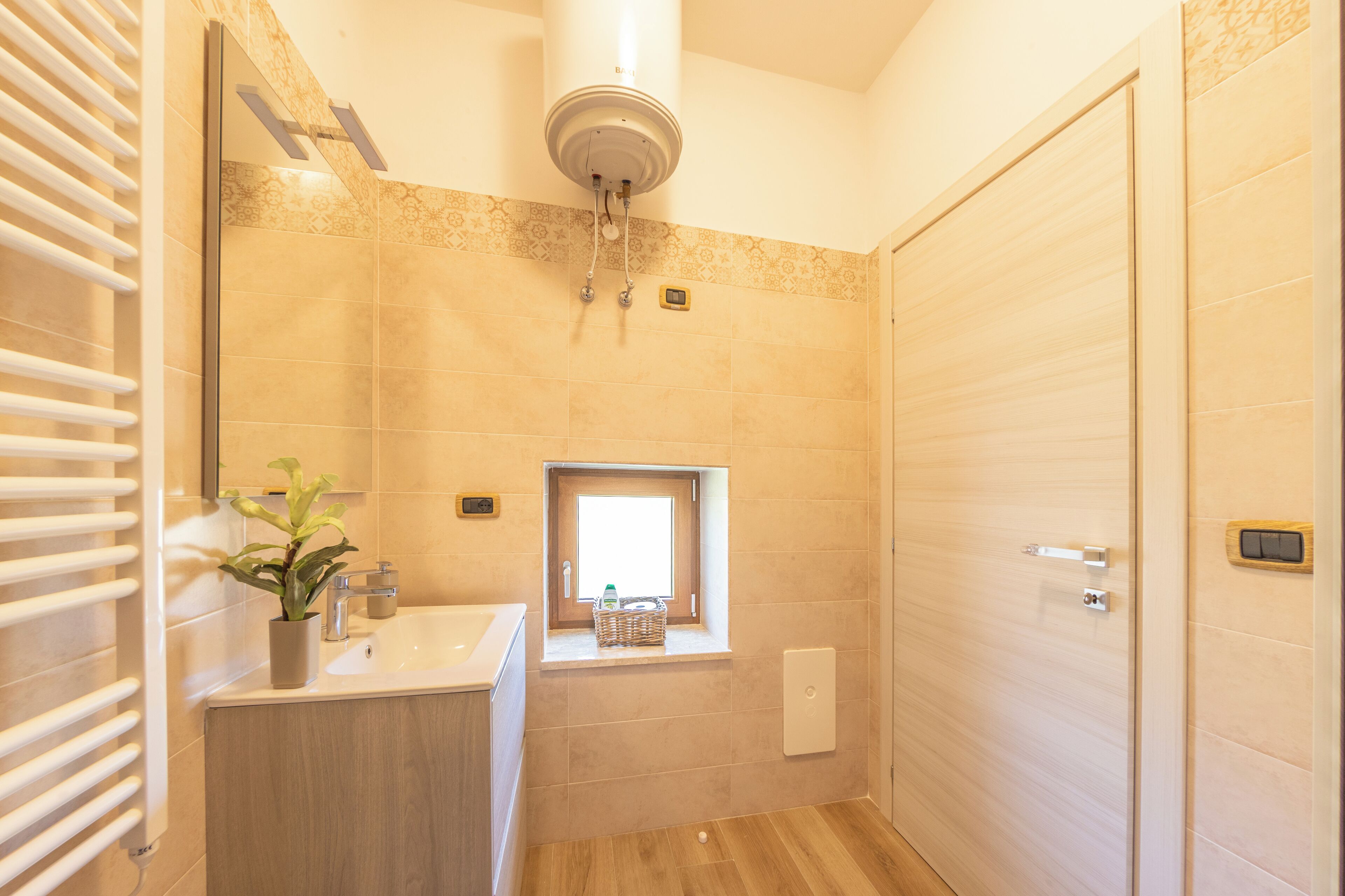 Ein Badezimmer mit Holzboden, einem Waschbecken mit Spiegel, einem Handtuchhalter und einem Fenster mit Blick.