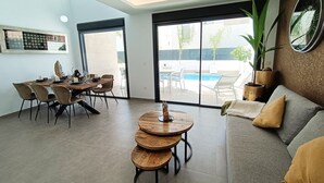 Een moderne woonkamer met een eethoek, uitzicht op een zwembad en een grote spiegel.