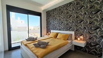 A modern bedroom with a large bed, a sliding glass door, a patterned wall, and bedside lamps.