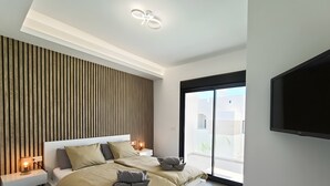 Een moderne slaapkamer met een bed, nachtkastjes, een tv aan de muur en een groot raam.