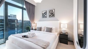 Ett modernt hotellrum med en stor säng, två sänglampor och utsikt över staden genom fönster som sträcker sig från golv till tak.
