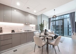 Una cuina moderna amb una illa central, electrodomèstics integrats i una zona de menjador amb taula preparada per a quatre.