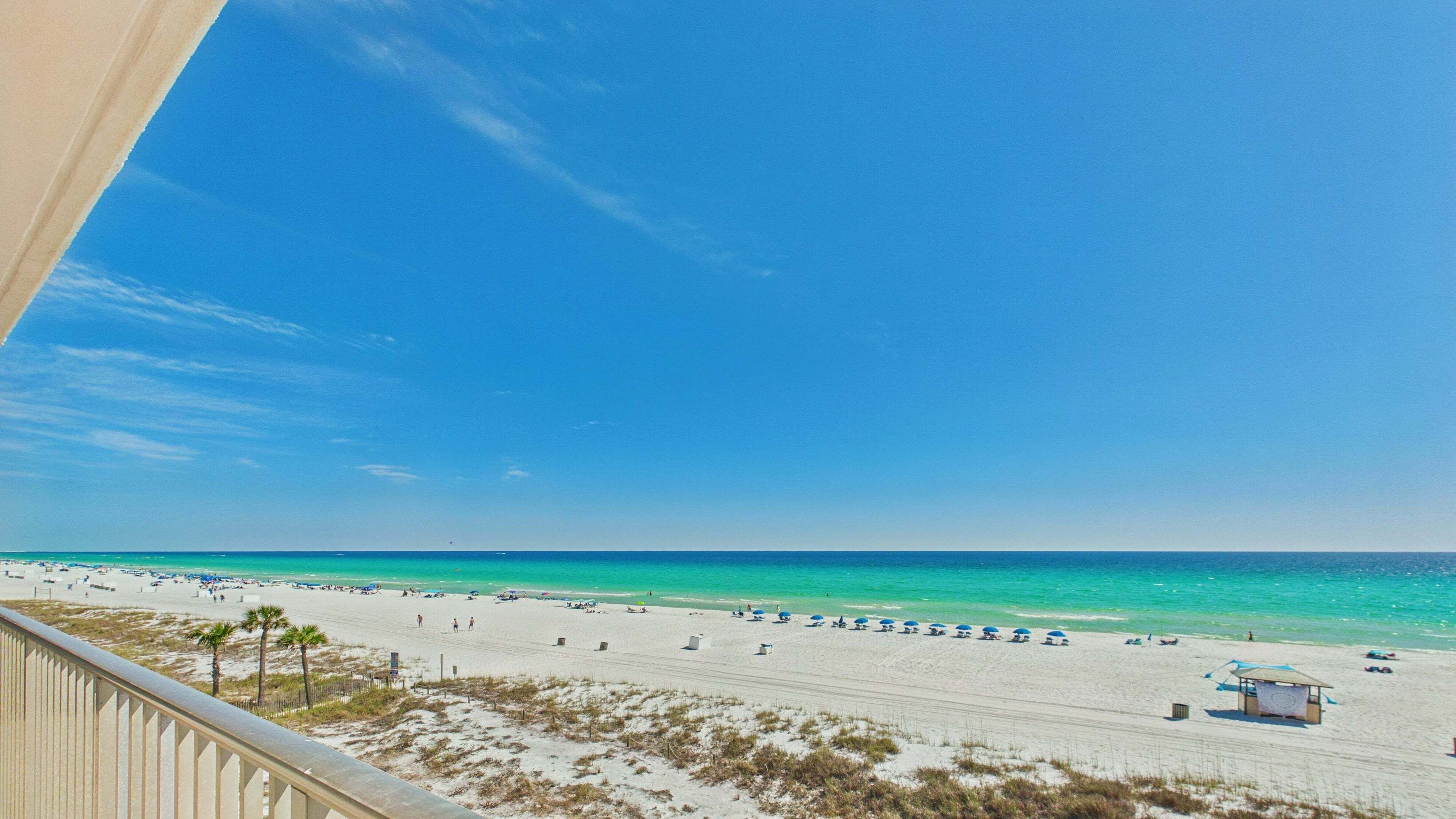 A beach with clear skies, a sandy shore, and a lifeguard station.