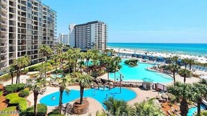 Un complexe hôtelier doté de plusieurs piscines, de palmiers et offrant une vue sur la plage.