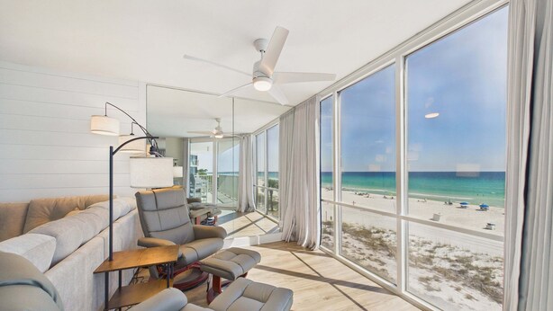 Un salon moderne doté d’une grande fenêtre donnant sur une plage.