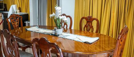A dining room with a wooden table and chairs, yellow curtains, and a ceiling light.