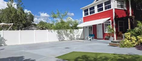 A two-story house with a red and white exterior, a covered patio with outdoor furniture, and a well-maintained lawn.