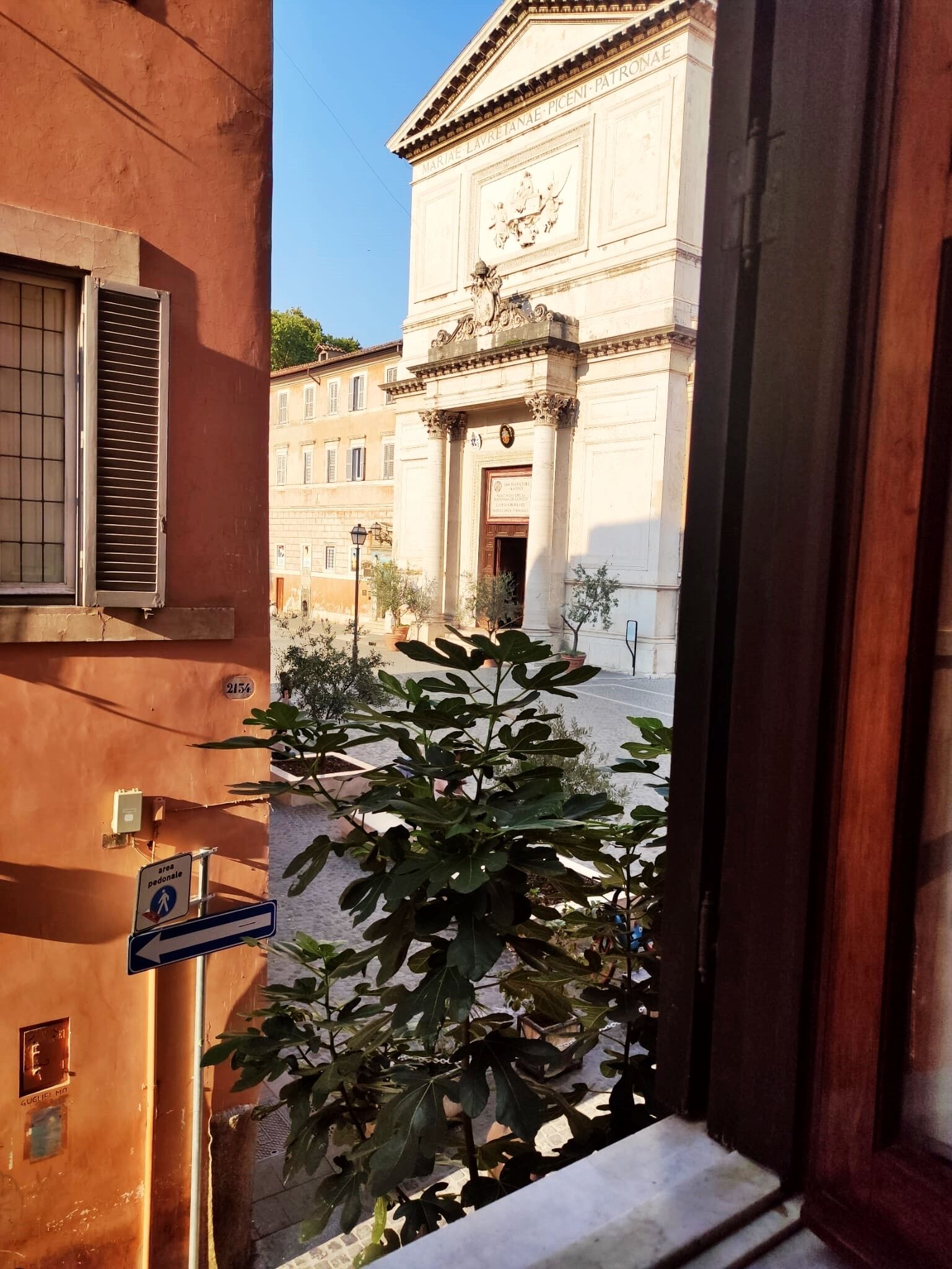 Vista de un edificio con fachada clásica, una señal de zona peatonal y un ventanal con persianas.