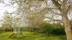 A swing set in a grassy area with trees and a clear sky. - Gîte du Maroye with Pool (Montreuil)