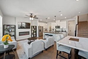 A modern kitchen with white cabinets, stainless steel appliances, and a central island. - PL088 | Plano | 4BD | Corporate Townhome | Garage (Plano)