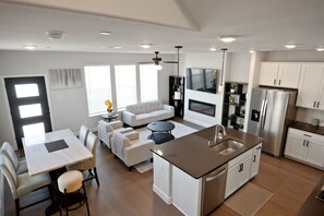 A modern kitchen with a central island, white cabinetry, and stainless steel appliances. - PL088 | Plano | 4BD | Corporate Townhome | Garage (Plano)
