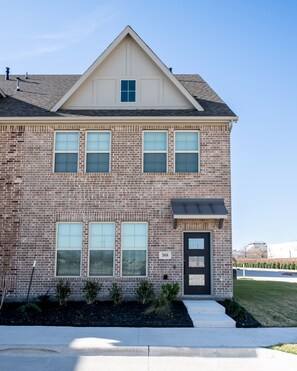 A two-story brick building with a gabled roof, a front door, and a small porch. - PL088 - Home|Yard|16mi to Convention Ctr|Sleeps 8 (Plano)