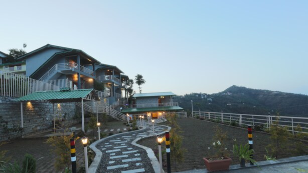 A hotel with a stone facade, multiple balconies, and a winding pathway leading to the entrance. - THE MOKSH ECO INN (Dhari)