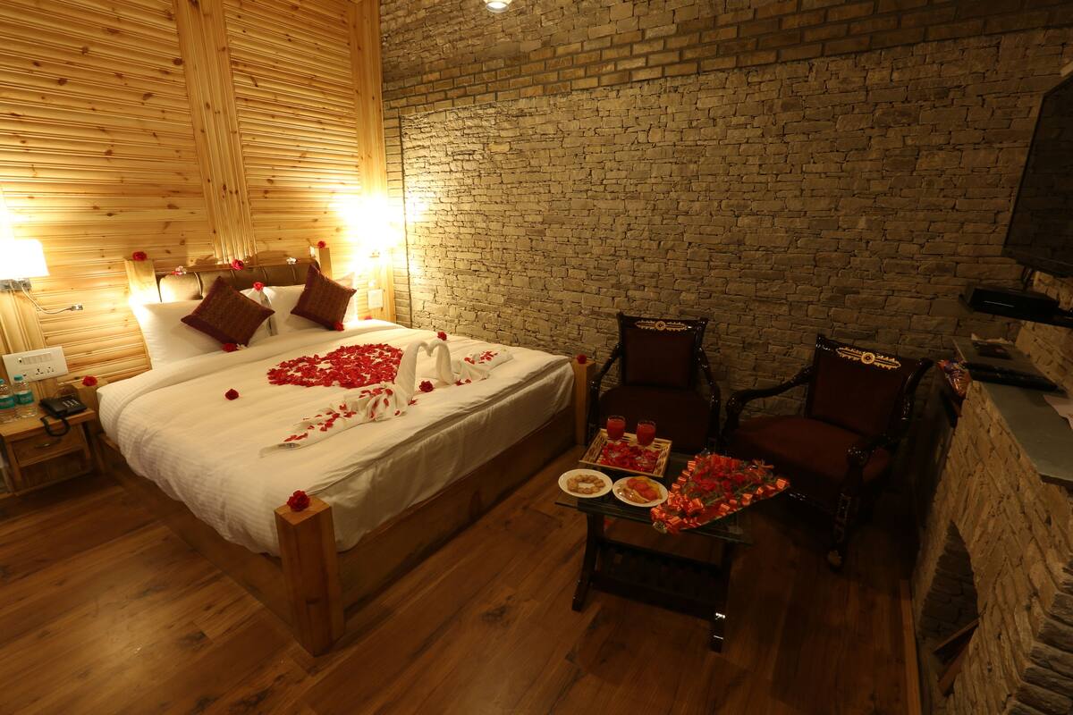 A cozy room with a wooden bed, a brick wall, and a fireplace.