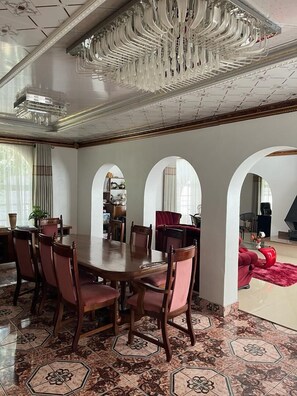A dining area with a large wooden table and chairs, surrounded by white walls and arched doorways. - 4-bedroom Retreat With Lush Gardens Pool- 2346 (Harare)