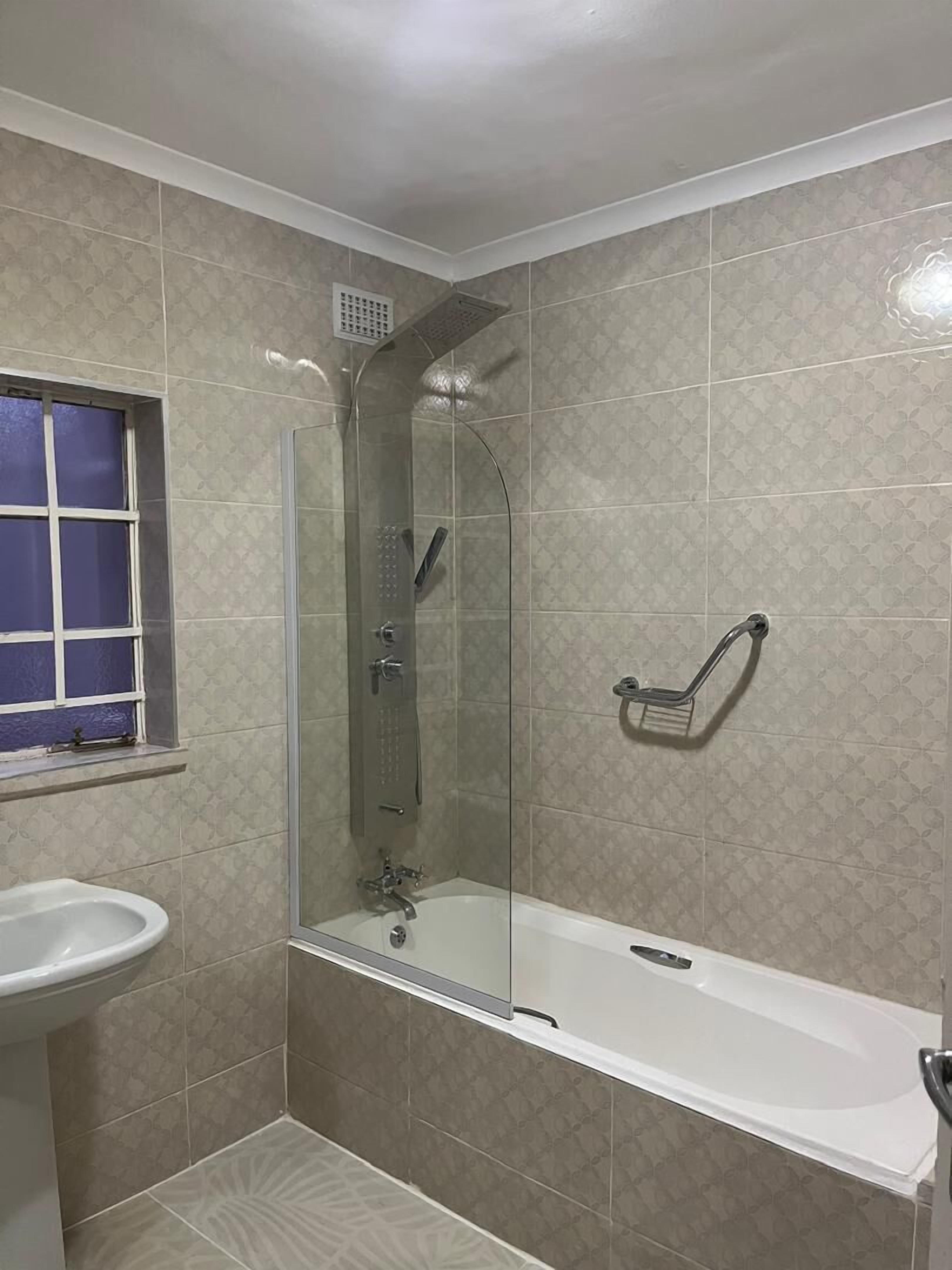 A bathroom with a glass-enclosed shower, a white bathtub, and a pedestal sink.
