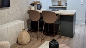 Une cuisine moderne avec un coin repas, comprenant un téléviseur à écran plat, un four à micro-ondes et un évier.