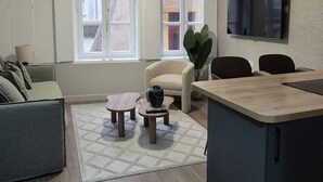 Un salon moderne comprenant un canapé, une table basse et un coin repas avec des chaises.
