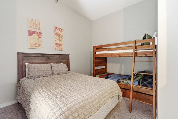 Ein Schlafzimmer mit Etagenbett, Einzelbett und zwei Bildern an der Wand.