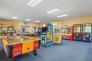 A room with various arcade games, a pool table, and a door leading to another room. - Lincoln Retreat | Pools, Gym, Sauna & Arcade (Lincoln)
