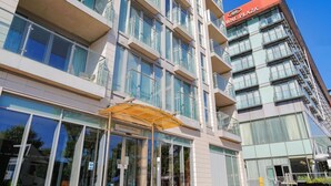 A modern building with a glass facade, a sign for 'WNE Plaza,' and a covered entrance labeled '18 Western Gateway.' - O2 & ExCeL! Modern 1 Bed Flat + Sofa Bed • Ideal for Conferences & Families (London)