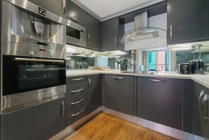 Eine moderne Küche mit Edelstahlgeräten, dunklen Schränken und Holzboden.