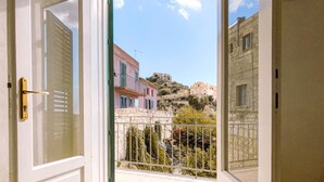 Une pièce avec une porte blanche donnant sur un balcon où se trouve un tapis bleu.