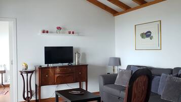 A living room with a television, a sofa, a patterned armchair, a coffee table, and a red rug.