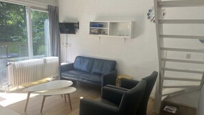 A living room with a grey sofa, a small table, and a white cabinet against the wall.
