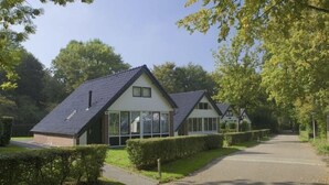 A row of houses with pitched roofs and large windows, surrounded by well-maintained hedges and trees.