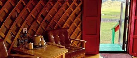 A cozy interior with a wooden table and chairs, a bench, and a doorway leading outside.