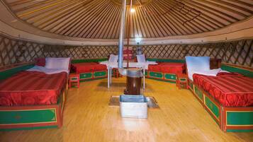 A yurt with four beds, a central stove, and a lattice wall.