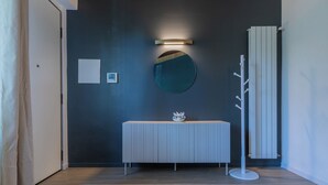 Un baño moderno con una pared oscura, un espejo redondo, un lavabo blanco y un perchero para toallas.