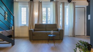Una sala de estar con un sofá, una mesita con vasos, una escalera y una puerta.