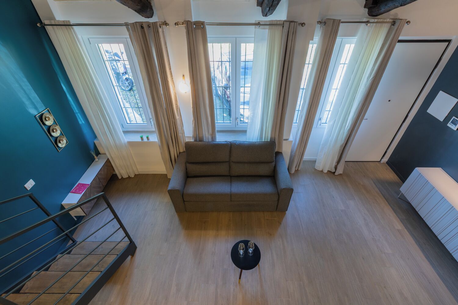 Un salon moderne avec un canapé, une petite table avec des verres et un escalier.