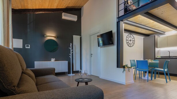 Una sala de estar moderna con un sofá, una mesa de centro y un comedor con sillas azules y una mesa pequeña.