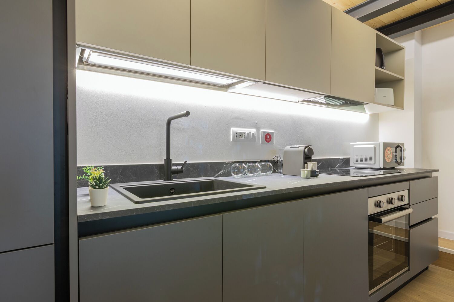 A modern kitchen with a stainless steel sink, a built-in oven, and a microwave.