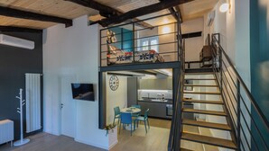 Un loft moderno con techo de madera, una cocina con comedor y una escalera.