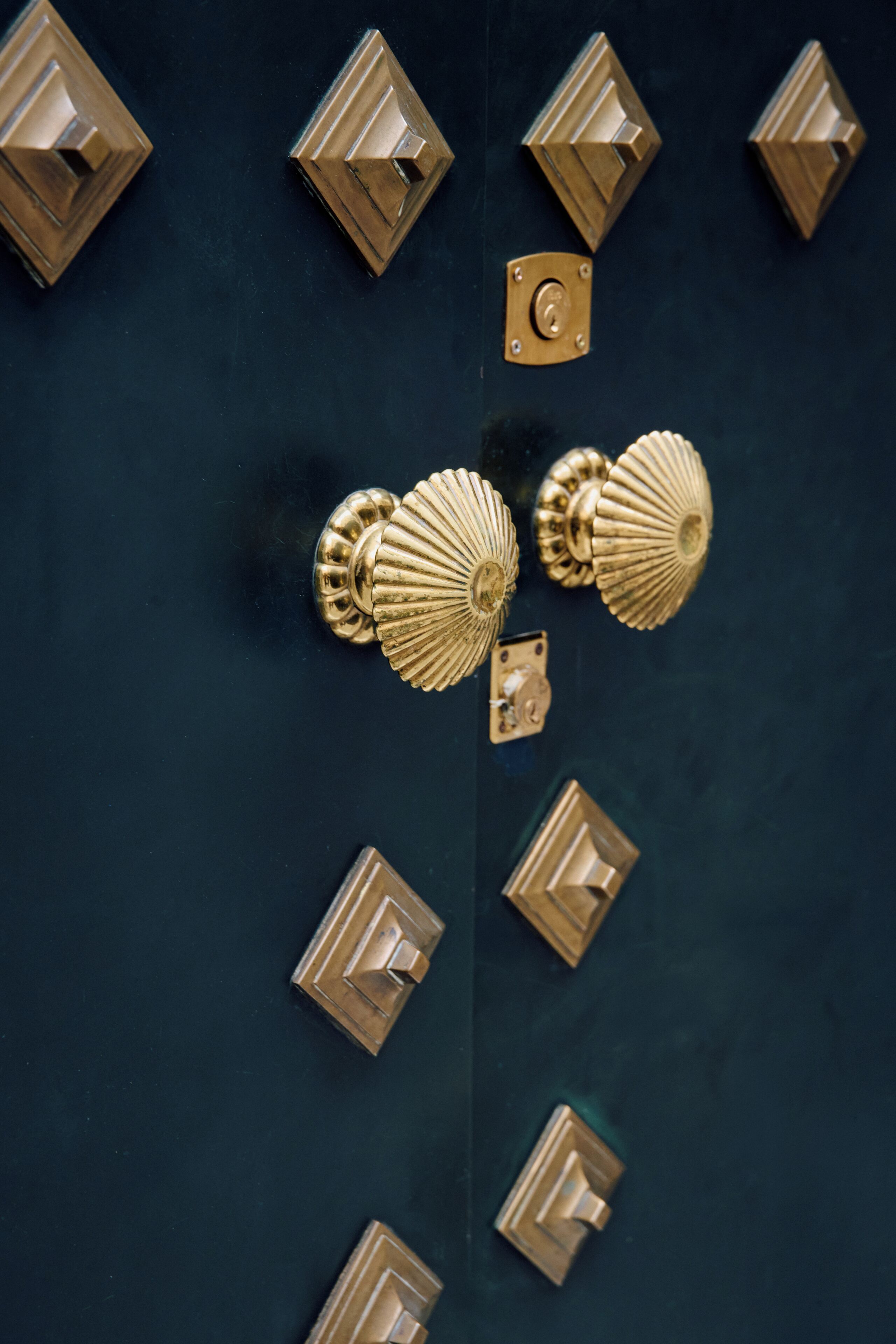 A set of brass door handles and locks on a dark door.