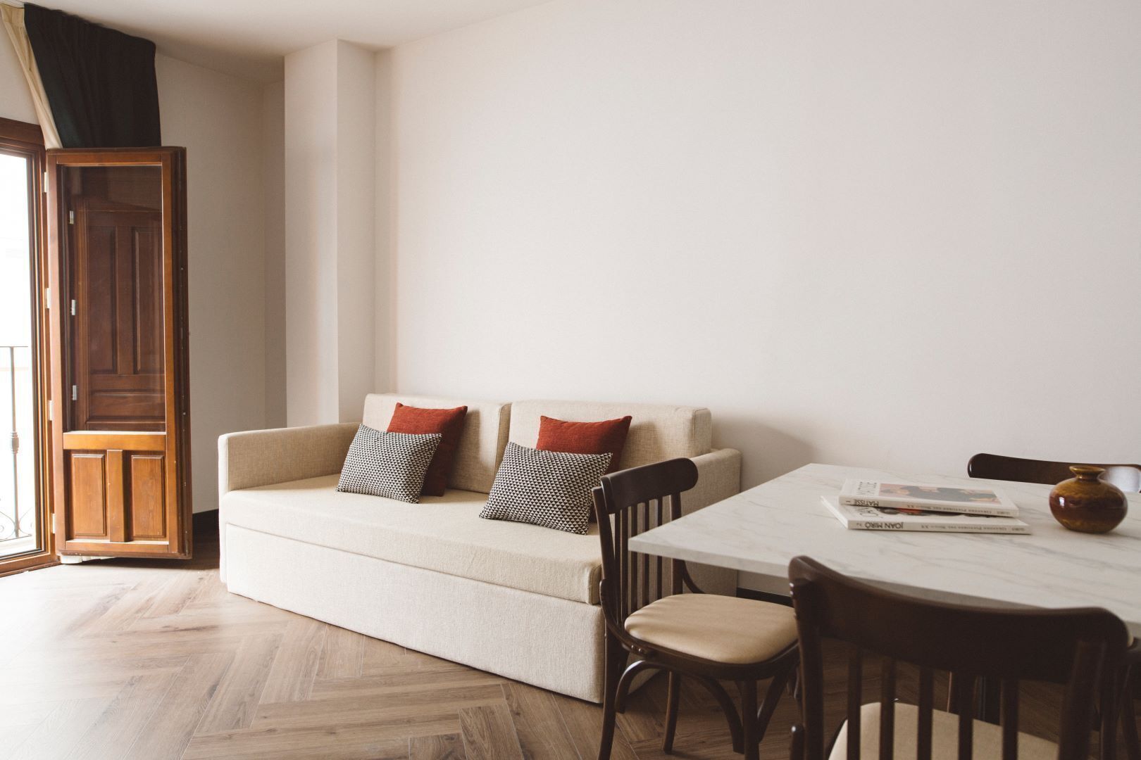 A living room with a sofa, two pillows, a table, and a chair.